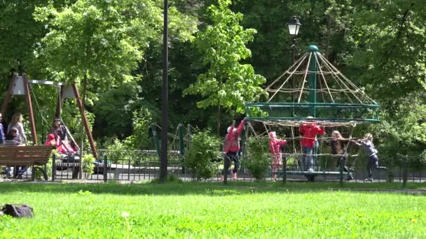 Los niños juegan en el patio de recreo con carrusel de cuerda oscilante. 4K — Vídeos de Stock