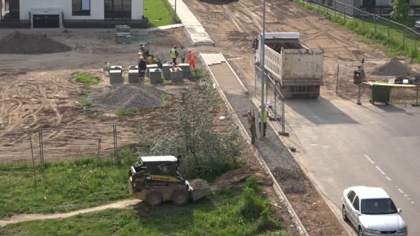 Grupo de trabajadores hacen pavimento de la acera de baldosas cerca de nuevas casas planas. 4K — Vídeo de stock