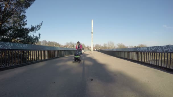 Mensen lopen voetgangersbrug over rivier in de lente avond. 4k — Stockvideo