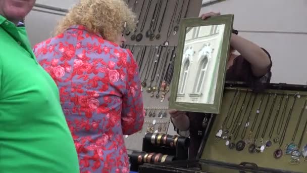 Femme mettre des boucles d'oreilles et regarder miroir dans la foire du marché extérieur. 4K — Video