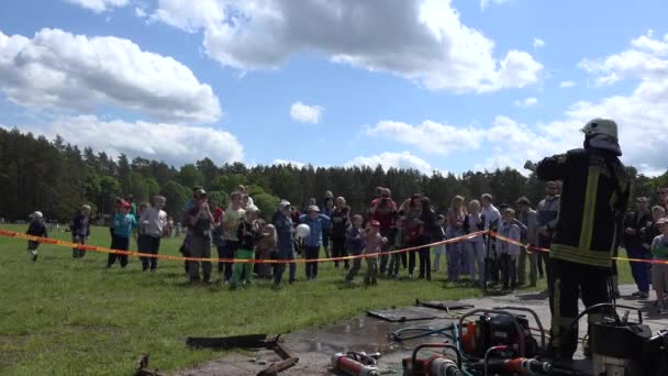 Pogodne dzieci odświeżają się pod wodą z pistoletu węża strażniczego. 4K — Wideo stockowe