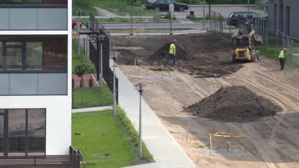 Paisajistas trabajadores preparan el suelo a lo largo de nuevas casas planas. 4K — Vídeo de stock