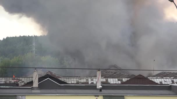 지붕에서 검은 연기가 솟아오르는 공장 건물을 불태우고 있습니다. 4k — 비디오