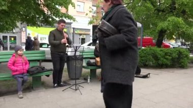 Genç aile, Litvanya halk enstrümanlarıyla sokaklarda gösteri yapıyor. 4K