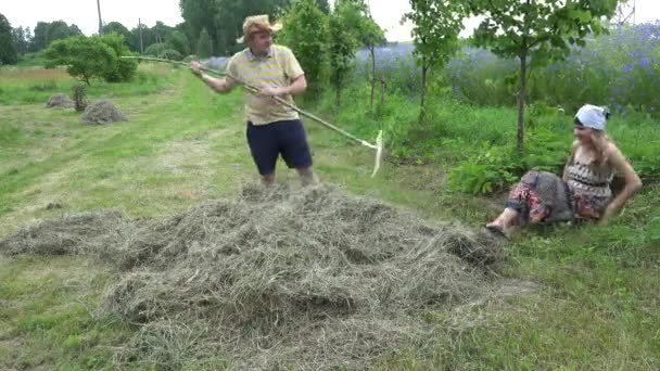 Playful farmer peasant couple man and woman rake hay in summer. 4K — Stock Video