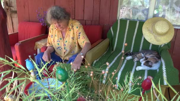 Женщина готовит лекарства ромашковые букеты с видом на деревню. 4K — стоковое видео