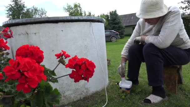 Mujer campesina mayor con pintura de pincel casa bien en el patio de la granja. 4K — Vídeos de Stock