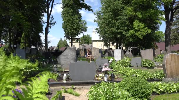 La donna in lutto si restringe vicino a tomba di marito di padre in cimitero. 4K — Video Stock