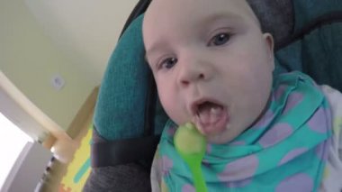Closeup beş aylık kafkas kız bebek veya erkek kaşık beslenen. 4k