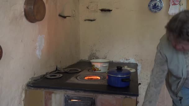 할머니 여자는 오래된 용광로 난로 화재에 냄비에 요리. 4k — 비디오