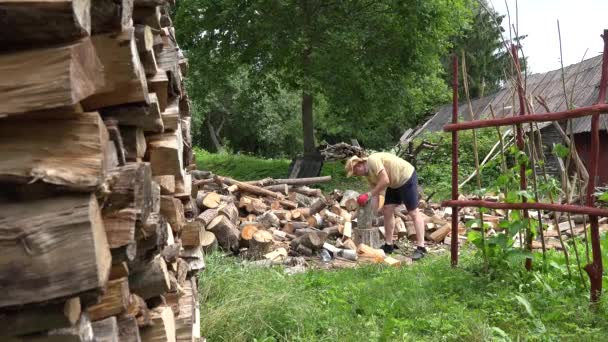 Крестьянин в шортах готовит дрова в деревенском доме. 4K — стоковое видео