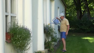 Saksı bahçe ev pencere eşikleri üzerinde sulama şort çiçekçi adam. 4k