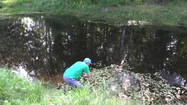 Αρσενικό κηπουρός καθαρή σκουπίδια και τα φυτά από την ιδιωτική λίμνη. 4k — Αρχείο Βίντεο