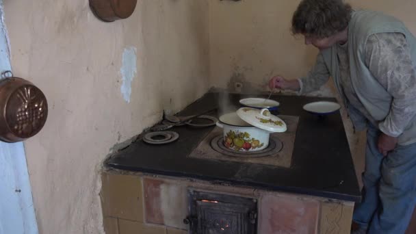 Mujer mayor cocinando en ollas en el fuego de la estufa del horno viejo. 4K — Vídeos de Stock