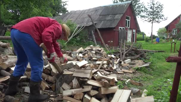 Stackars bonde man chop trä nära landsbygdens hus. 4k — Stockvideo