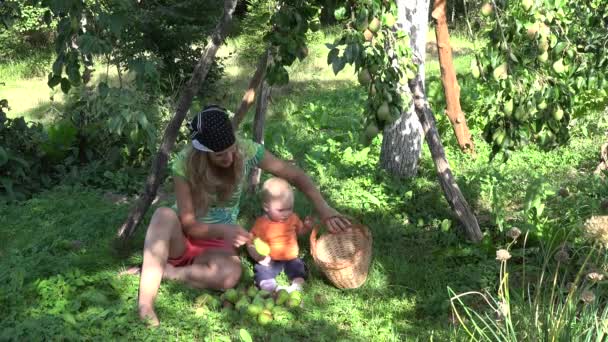 妈妈和她的小女儿在果园里把梨果摘到果园的果子下。4k — 图库视频影像