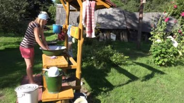 Zavallı yalnız köylü kadın çiftlik bahçesinde metal kase de elle çamaşır yıkama. 4k