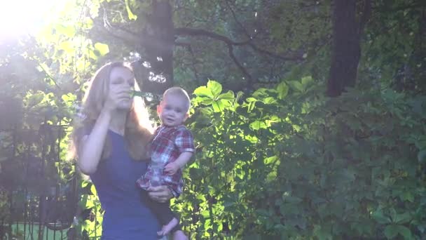 Madre soplando burbujas de jabón con la hija bebé en las manos en la hermosa luz del sol por la noche. 4K — Vídeo de stock