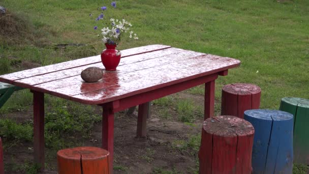 Gota de chuva em toco de mesa de madeira vermelha no pátio verde da aldeia. 4K — Vídeo de Stock