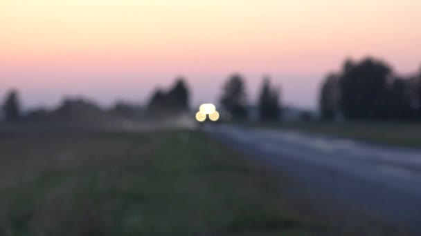 Rozmazané sklízecí stroj jízdu na silnici s velkými světla na večerní slunce. 4k — Stock video