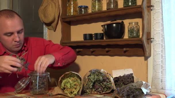 Herboriste gars mis marjolaine séchée herbes dans un bocal en verre. 4K — Video