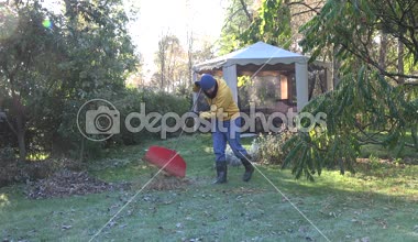 Bahçıvan sıcak giysiler komisyon yaprakları sonbaharda buzlu Bahçe çim üzerinde. 4k