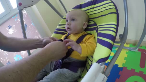 Padre hombre puso bebé recién nacido en swing y clip cinturón de seguridad. 4K — Vídeo de stock