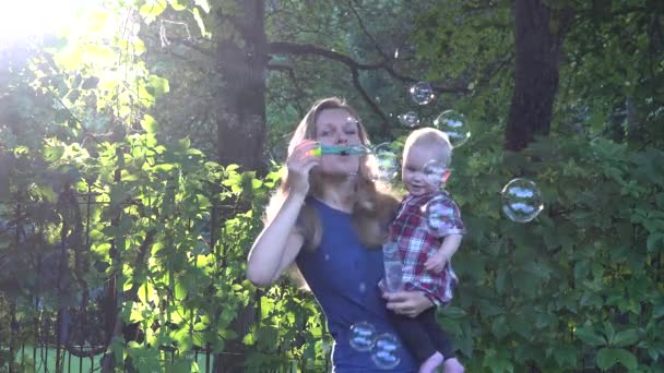 Mère avec bébé fille souffler bulle de savon dans le parc ensoleillé du soir. 4K — Video