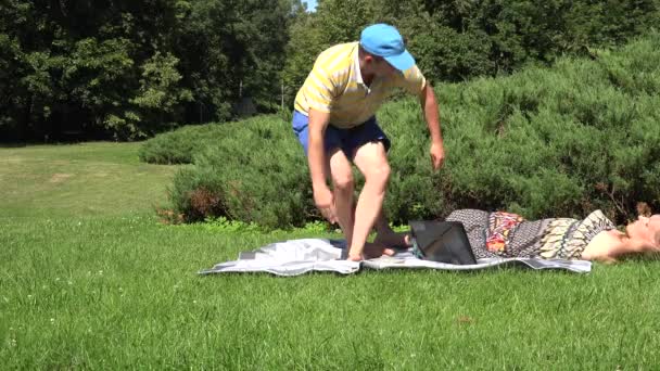 Pareja descansando con libro y computadora en el parque natural de verano. 4K — Vídeos de Stock