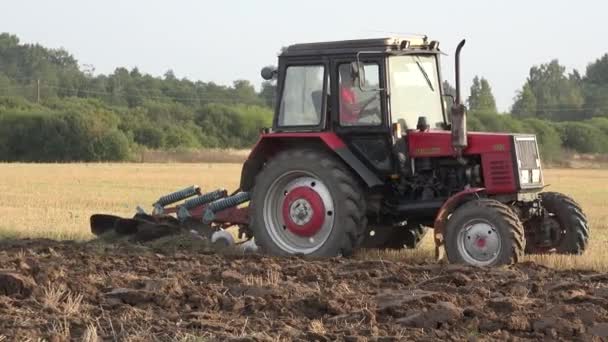 Campo de rastrojo de arado de granjero con tractor rojo. Panorama. 4K — Vídeo de stock