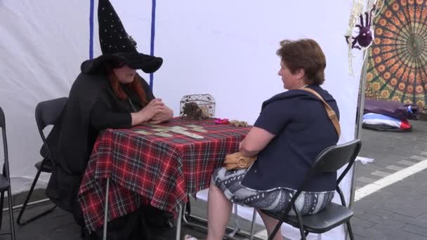 Czytnik kart kobieta czarownica z kapeluszem przewidzieć przyszłość w plenerze festiwalu. 4K — Wideo stockowe