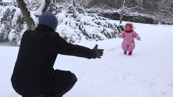 Happy baby girl walk towards father on snow in winter season. 4K — стоковое видео