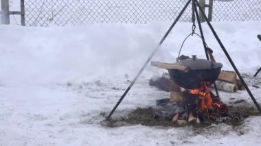 Turist pot bir kamp ateşi üzerinde yemek kış aylarında ateşin üzerinde asılı. 4k