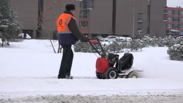 Werknemer man met sneeuwblazer schone sneeuw van voetpad. auto rijden op straat. 4k — Stockvideo