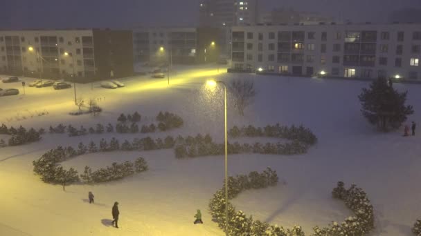 La gente disfruta del invierno en el patio del distrito de la casa plana en la tormenta de nieve pesada. 4K — Vídeo de stock