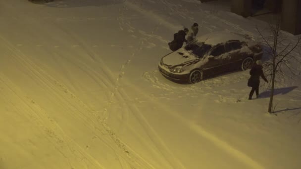 家族の人は、冬の夜にフラットの家地区に車から雪をきれい。4 k — ストック動画