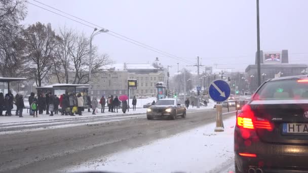 人们等待公交车后的工作和在下大雪的街道上行驶的汽车。4 k — 图库视频影像