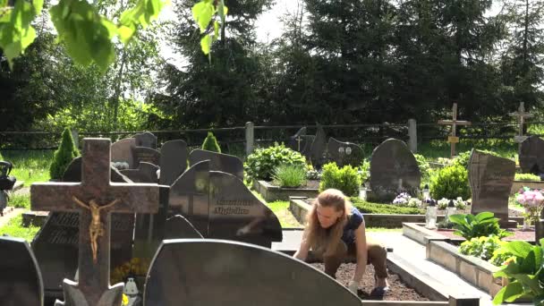 Jeune femme fille soins houe mari tombe dans le cimetière. 4K — Video