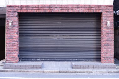 Fabrikada, depoda, garajda ve endüstriyel depoda kullanılan otomatik metal paten kapısının yakın çekimi. Bükülebilir ve katlanabilir metal levha yer tasarrufu sunuyor ve kentsel ve kırsal hissi sağlıyor