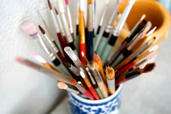Detail of paint brushes and bright paint in a artists studio