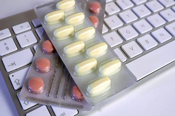 Tabletki leżące na klawiaturze komputera — Zdjęcie stockowe