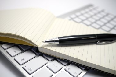 notepad and pen on a computer keyboard