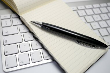 notepad and pen on a computer keyboard