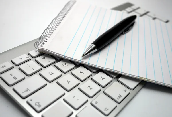 Bloc de notas y pluma en un teclado de computadora — Foto de Stock