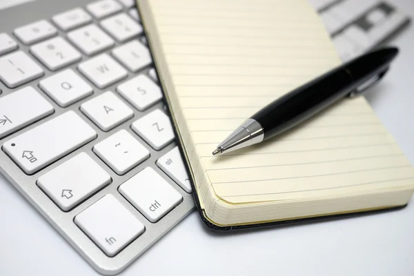 Bloc de notas y pluma en un teclado de computadora — Foto de Stock