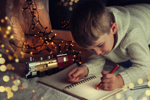 Küçük çocuk Noel Baba'ya mektup yazar