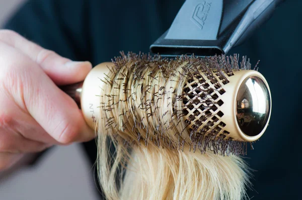 Secagem de cabelo loiro com secador de cabelo e escova redonda . — Fotografia de Stock