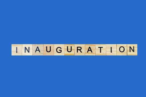Inauguration . English word on blue background composed from letters on wooden cubes. Learning english concept