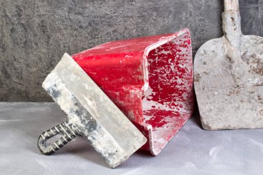 Bina aletleri eski, kirli kürek, kırmızı kova, gri beton arka planda tuğlalar. Uzayı kopyala Üst görünüm