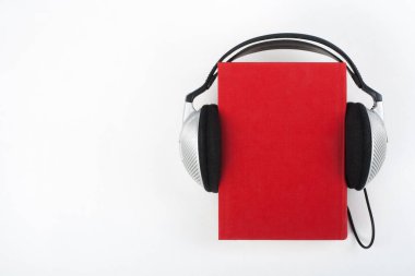 Beyaz arka planda Audiobook. Kulaklıklar mavi kaplı defter, boş kapak, reklam metni için kopyalama alanı. Uzaklık eğitimi, e-öğrenme kavramı